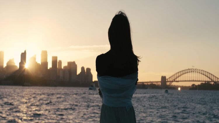 日落时从湖对面看城市的女人