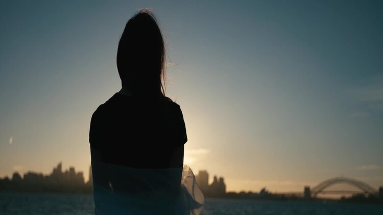 日落时分，一个女人站在那儿看着远处的城市