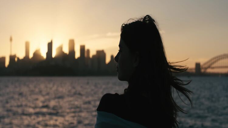 夕阳西下时，女人站在河对岸望着城市